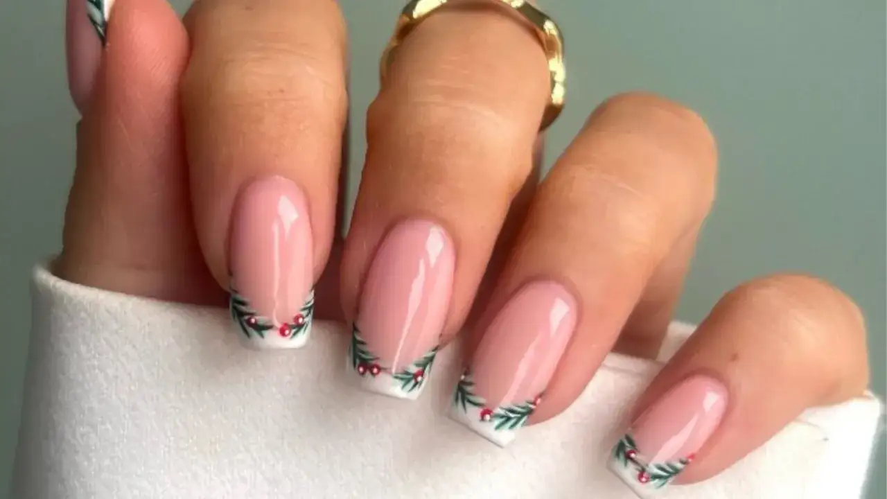 Dłonie z eleganckim french manicure, ozdobione zimową gałązką ostrokrzewu z czerwonymi koralikami. Idealny french na święta!