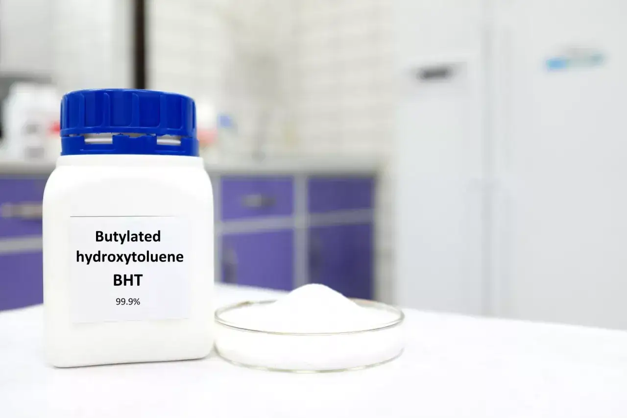 Biały proszek BHT (butylated hydroxytoluene) w laboratorium, składnik wielu kosmetyków.