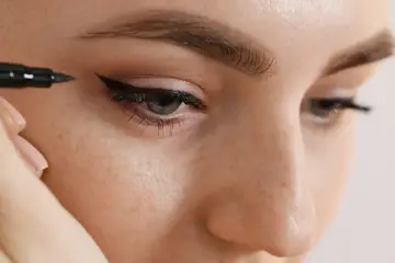 Precyzyjne malowanie kreski eyelinerem, podkreślające spojrzenie.
